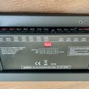 Záběr na zadní panel černého elektronického zařízení. Na povrchu jsou tabulky s technickými specifikacemi napětí a proudu, nápis „www.Truestone.com“…