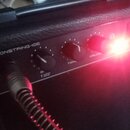 Černý kytarový kombozesilovač s texturovaným povrchem. Na horním panelu je bílý nápis VISIONSTRING-10E a tři ovládací knoflíky s popisky TONE, VOLUME…