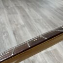 Detailní pohled na hриф kytary s tmavým dřevěným hmatníkem a světlými polohovými značkami. Na hmatníku jsou vidět kovové pražce a struny. Povrch krku…