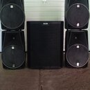 Pět černých reproduktorů v plastových skříních. Uprostřed stojí jeden velký subwoofer s nápisem ALTO, po stranách jsou dva sloupce dvou menších repro…