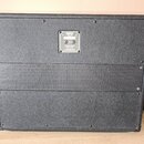 Zadní strana kytarového cabinetu potaženého černým textilem. Uprostřed je umístěn kovový štítek s nápisy: "ORANGE", "CE", "Made in China", "120W 8OHM…