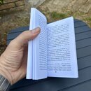 Fotografie zachycuje otevřenou knihu s textem v češtině, kterou drží ruka s náramkovou hodinkou. Text na stránkách se zabývá hudební tematikou, je zd…