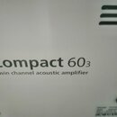 Detailní záběr na bílý povrch akustického zesilovače. Na přístroji je černý nápis „Compact 60₃“ a pod ním text „twin channel acoustic amplifier“. V p…