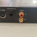 Detailní pohled na zadní panel černého elektronického zařízení. Jsou vidět konektory s popisky MIDI OUT / THRU, FOOTSWITCH a S/PDIF s rozdělením na I…