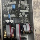 Fotografie zachycuje vnitřek efektpedálu v hliníkovém šasi. Na černé základní desce jsou připájené elektronické součástky a bílý nápis Darkglass Elec…