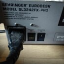 Detail zadní strany zařízení v šedé barvě. Je na něm vidět nápis BEHRINGER EURODESK MODEL SL3242FX-PRO a text CONCEIVED AND DESIGNED BY BEHRINGER GER…