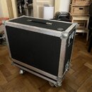 Černý transportní flightcase s hliníkovými hranami a kovovými rohy. Bedna je vybavena horní rukojetí a spodními kolečky. Na pravém horním boku je umí…