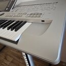Stříbrný digitální klavír s bílými a černými klávesami. Na horním panelu je vidět nápis MOTIF ES8 a ovládací prvky s popisky jako TOUCH SETTING, PART…
