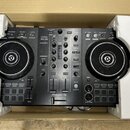 Černý DJ kontrolér Pioneer DJ DDJ-400 umístěný v přepravní krabici s bílými polystyrenovými vložkami. Na horní části je vidět nápis DDJ-400 a logo re…