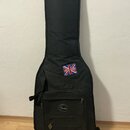 Černý polstrovaný obal na kytaru z textilního materiálu. V horní části je přišita nálepka s britskou vlajkou a nápisem UNITED KINGDOM. Na přední kaps…