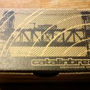 Kartonová krabice hnědé barvy s černým potiskem. Na povrchu je zobrazen grafický motiv mostu a nápisy „catalinbread“ a „MECHANISMS OF MUSIC“. Hrany k…
