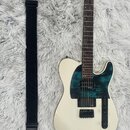 Bílá elektrická kytara s tmelelovým hmatníkem a tmavě modrým pickguardem. Nástroj má jeden humbucker v pozici kobylky a jeden snímač u krku. Vedle ky…