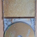 Otevřené plastové CD pouzdro s vloženým zlatavým bookletem a kompaktním discem. Na discu je bílý nápis christmas pop a logo SONY MUSIC. Booklet má zl…