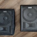 Dva černé reproduktorové boxy s kovovými ochrannými mřížkami. Na horní části každého boxu je umístěno oválné logo s nápisem Soundking. Povrch krytů v…