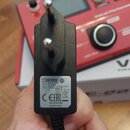 Černý síťový adaptér s kolmíkovým konektorem. Na bílém štítku je uveden nápis BOSS, SWITCHING ADAPTER, MODEL: PSA-230PV, INPUT: 100-240V ~ 50-60Hz 25…