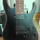 Elektrická kytara s černým matným povrchem těla a hnědým hmatníkem. Nástroj má dva snímače typu humbucker a černý tremolo systém s páčkou. Na těle js…