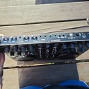 Zadní strana černého DJ mixeru s řadou konektorů a ovládacích prvků. Na horní hraně jsou vidět nápisy DESIGNED BY RELOOP GERMANY, www.reloop.com a mo…