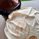 Bílá textilní brašna s oranžovým kruhovým potiskem, který obsahuje nápisy „Sonic Energy“ a „collection“ a logo značky „MEINL“. Vedle brašny leží malý…