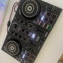 Černý DJ kontrolér s dvěma jog-koly, faderem a řadou tlačítek a knoflíků. Na přístroji jsou viditelné nápisy Hercules, DJCONTROL INPULSE 200 a DJUCED…