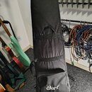 Černý polstrovaný obal na hudební nástroj z textilního materiálu. V dolní části je umístěno bílé logo Cort a pod ním webová adresa www.cortguitars.co…