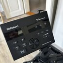 Černý elektronický bicí modul s nápisy Roland a V-Drums. Na spodní pravé straně je uveden model DRUM SOUND MODULE TD-07. Zařízení obsahuje několik ov…