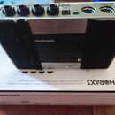 Zadní strana stříbrného efektového pedálu s černými tkanými bočními panely. Na horní hraně jsou konektory s popisky IN, OUTPUT, DC IN 9V 600mA, MIDI…