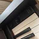 Detailní pohled na ovládací panel a klávesy digitálního pianina v černé barvě. Na panelu je nápis ARRIUS YDP-S54, ovrtací knoflík s označením MASTER…