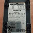 Fotografie zachycuje spodní stranu efekt pedálu značky BOSS. Uprostřed je bílý štítek s tabulkou pro BOSS PSA ADAPTOR, nápisem Dry battery 9V a varov…