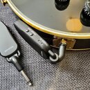 Dvě černé bezdrátové vysílače/přijímače s kovovými jack konektory. Na levém zařízení je nápis RECEIVER, na pravém jsou nápisy POWER PAIR, CHARGE ID a…