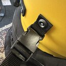 Detailní záběr na černý plastový přezkouškový zapínací mechanismus s textilním popruhem. Popruh je připevněn k žlutému povrchu nástroje pomocí kovové…