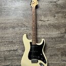 Elektrická kytara s krémovým tělem a černým pickguardem. Na hlavě hmatníku je nápis Tokai SUPER STRAT. Hmatník je vyroben z tmavého dřeva a nástroj m…