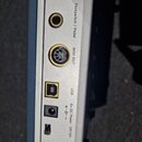 Detail zadní strany stříbrného zařízení s řadou konektorů. Jsou zde viditelné nápisy Footswitch / Pedal, MIDI OUT, USB a 6V DC Power s označením pola…
