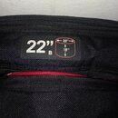 Detail černé texturované látky s přišitou černou štítkem. Na štítku je bílý nápis 22" B a schéma obdélníku s rozměry 22" a 18". Pod štítkem je vidite…