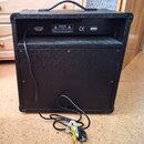 Zadní strana černého kytarového komba s texturovaným povrchem a přenosnou rukojetí. V horní části jsou bílé nápisy „INPUT POWER 230VAC ~ 50Hz 80W MAX…