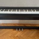 Černý digitální piano s bílo-černou klaviaturou a integrovaným stojanem. V pravém horním rohu je bílé logo Roland. Nástroj má v horní části řadu ovlá…