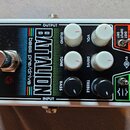 Bílý efekt pedál s černým předním panelem a nápisy Electro-Harmonix NEW YORK CITY, USA a BATALION bass pre/drive. Na panelu jsou čtyři bílé a dva čer…