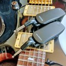 Dva černé bezdrátové vysílače s kovovými konektory, položené na černé elektrické kytáře se zlatým hardwarem. Na horním zařízení je nápis RECEIVER a n…