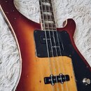 Elektrická basová kytara s tělem v červeně-žlutém sunburst provedení a černým pickguardem. Nástroj má čtyři struny, dva snímače a jeden ovládací knof…