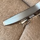 Detailní pohled na hranu černého hudebního nástroje s viditelnou strukturou dřeva. Na hraně je v levé části patrné opotřebení a odbarvení laku. V pra…