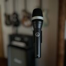 Černý dynamický mikrofon s mřížkou a bílým prstenem v horní části. Na těle je viditelné logo AKG a nápis D 5. Povrch mikrofonu je matný a v dobrém st…