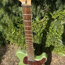 Zelená elektrická kytara s tvarem typu Telecaster a hnědým pickguardem z materiálu imitující želvu. Hmatník je vyroben z tmavého dřeva a hlava z přír…