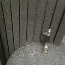 Fotografie zachycuje vnitřek černého polstrování z pěnového materiálu s vertikálními přepážkami. Uvnitř leží malý kovový předmět připomínající součás…