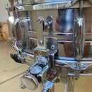Detailní pohled na chromovaný snare drum s kovovým korpusem. Na mechanismu uvnitř korpusu je viditelné logo „Star“ a pod ním menší nápis „TAMA“. Povr…