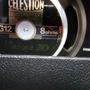 Detailní pohled na reproduktor s černým středovým krytem a stříbrným vnějším prstencem. Na krytu jsou nápisy CELESTION LOUDSPEAKERS, G12, 8ohms a v d…