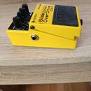 Žlutý efekt pedál s černým spínacím tlačítkem a čtyřmi černými ovládacími knoflíky. Na horní straně je nápis Bass OverDrive ODB-3 a na tlačítku logo…
