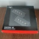 Černá krabička s červeným spodním okrajem obsahuje dva snímače pro basovou kytaru. Na přední straně krabičky je bílý nápis CUSTOM '62 PRECISION BASS…