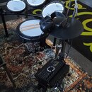 Elektronická bicí souprava značky Roland v černé barvě s bílými membránami. Na membránách a činelech je viditelné logo Roland. Součástí je černý ovlá…