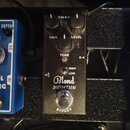 Černý efekt pedál s nápisy Blond DISTORTION a BYPASS. Na horní části jsou tři ovládací knoflíky s popisky GAIN, LEVEL a TONE, dále přepínač HIGH/LOW…