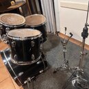 Sada černých bubnů včetně basového bubnu, dvou tom-tomů a jednoho deeper tomu. K nástrojům patří dva chromované stojany a černý kombo zesilovač s náp…