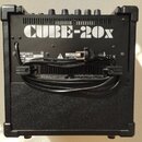 Zadní strana černého kytarového komba s nápisem CUBE-20x. Na zadním panelu je vidět logo Roland, varovný štítek CAUTION RISK OF ELECTRIC SHOCK DO NOT…
